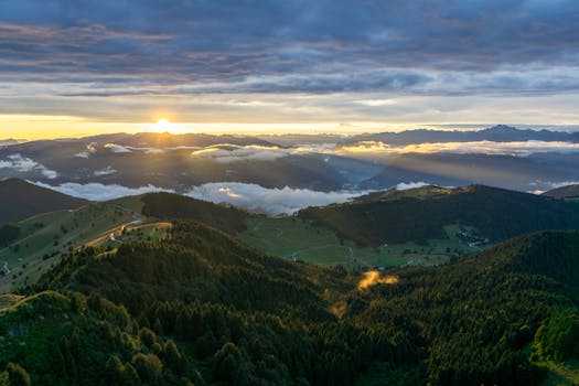 Capture the stunning sunrise over Monte Grappa in Veneto, Italy. Majestic mountains and serene clouds create a breathtaking view.