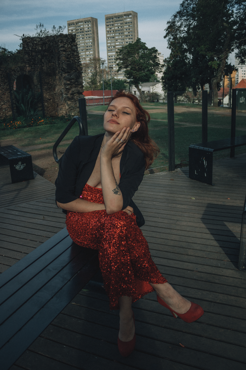 Free Stylish woman in red sequin dress relaxing on a wooden deck outdoors. Stock Photo