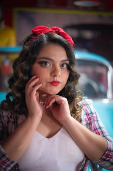 A retro-styled woman poses with curls and a red headband, exuding vintage charm.