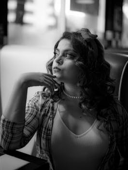Elegant black and white photo of a woman in thoughtful pose at a vintage diner.