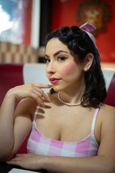 Portrait of a young woman in retro attire inside a vintage diner setting.