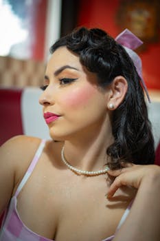 A woman in classic vintage attire and makeup poses elegantly indoors.