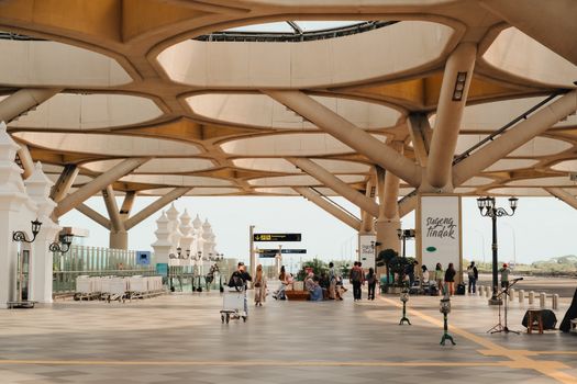 A spacious outdoor station with modern architectural design featuring intricate ceiling patterns and people in transit.