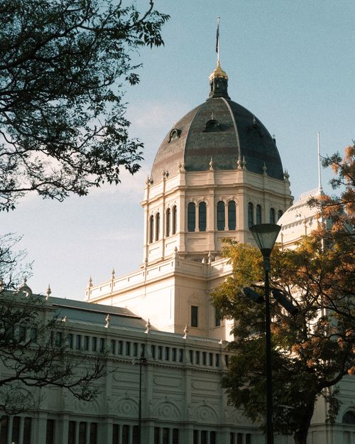 Free Sunlit view of the Royal Exhibition Building with trees in Melbourne, Australia. Stock Photo