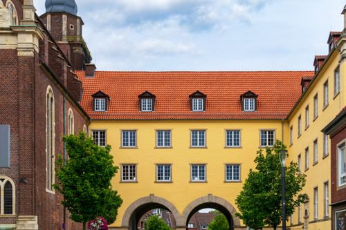 Free Vibrant yellow building facade with red roofs and arches in a European city setting. Stock Photo