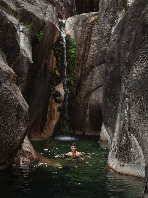 Free An adult male swims in a natural pool beneath a cascade waterfall in Vilar da Veiga, Portugal. Stock Photo