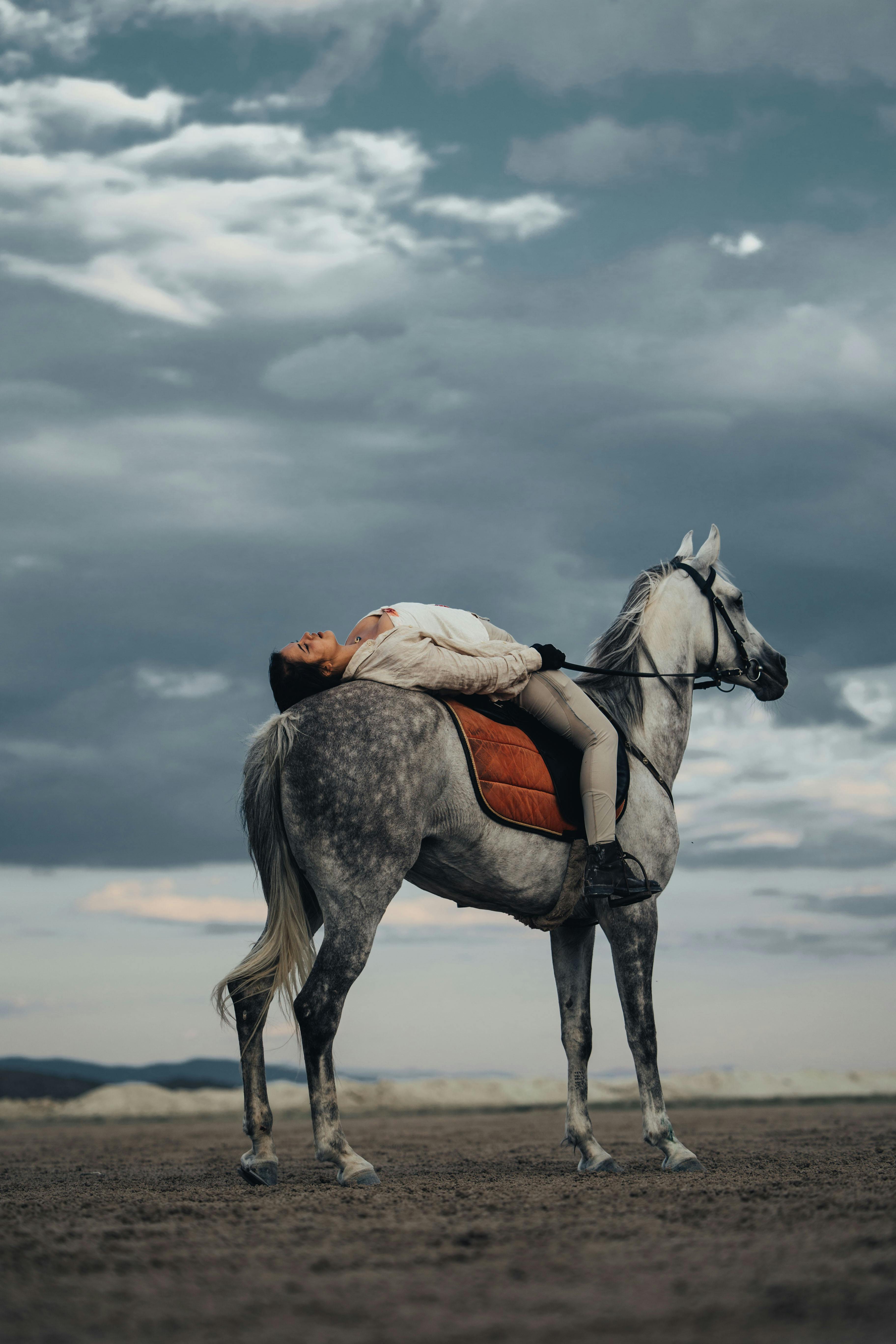 A woman lying back on a horse under a dramatic sky in Kayseri, Turkey.