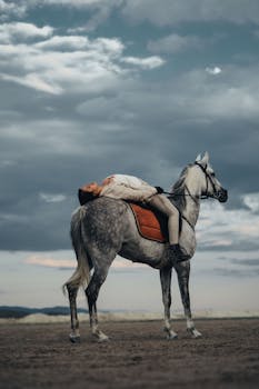 A woman lying back on a horse under a dramatic sky in Kayseri, Turkey.