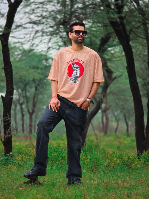 Free Man posing in casual attire among lush green forest trees, exuding a laid-back and stylish vibe. Stock Photo