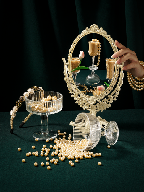Luxurious still life of pearls, ornate mirror, and champagne for a vintage aesthetic.