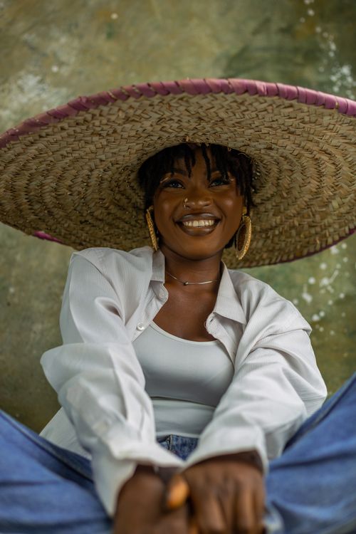 Free Portrait of a joyful woman wearing a large woven hat, radiating happiness. Stock Photo