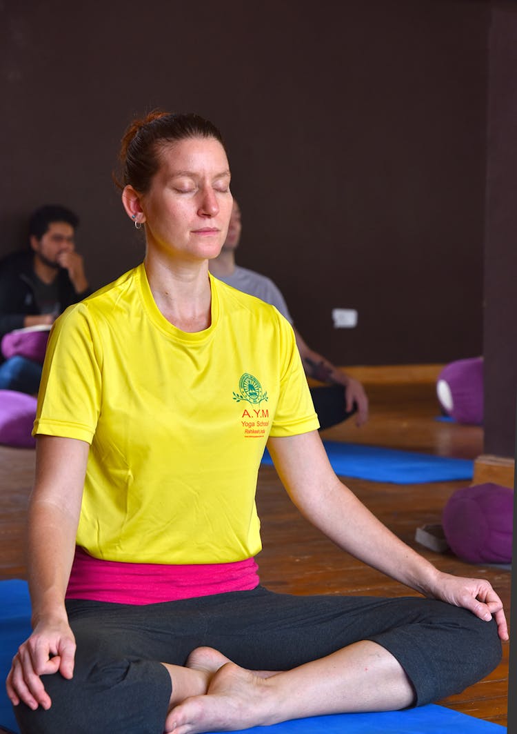 Woman In Yellow T-shirt Sitting On A Yoga Mat