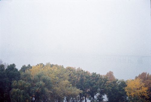 Free Mist envelops the river and trees in Dnipro during autumn, creating a serene landscape. Stock Photo