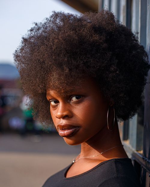 Free Stunning outdoor portrait of a woman with beautiful natural curly hair and hoop earrings. Stock Photo