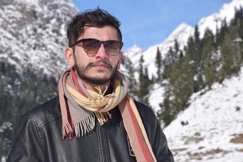 Free Portrait of a man with sunglasses and scarf against snowy mountains. Stock Photo