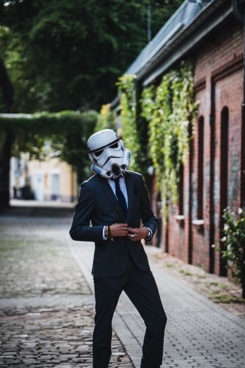 Free Man in suit wearing a Stormtrooper helmet on cobblestone street in Gütersloh, Germany. Stock Photo
