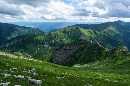 Free Breathtaking view of mountain ranges with lush greenery and rocky slopes under a cloudy sky. Stock Photo