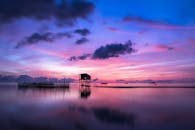 在色彩缤纷的天空倒影下，美丽的热带日落映衬着高跷和船只