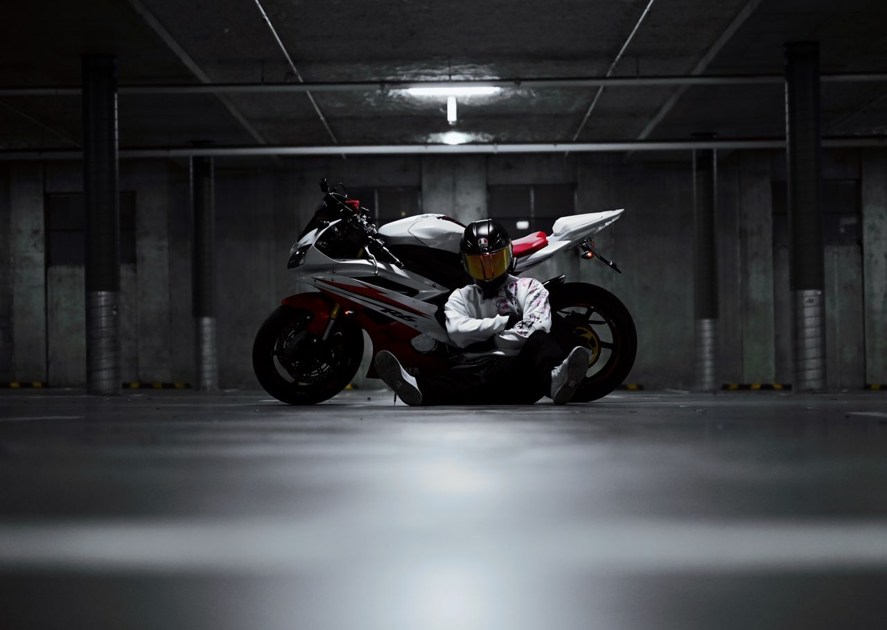 motorcyclist with helmet sits in dimly lit underground parking garage