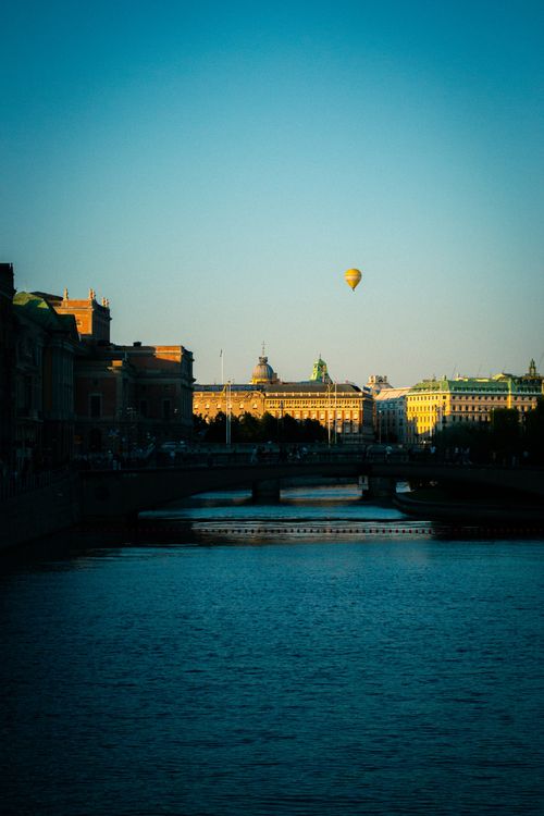 Free A hot air balloon floats over the water with historic Stockholm architecture at sunset. Stock Photo