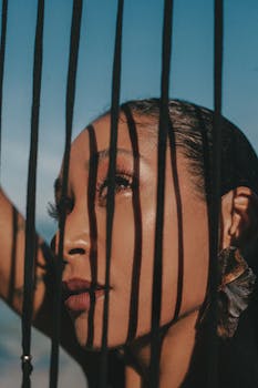 Close-up portrait of a woman with dramatic shadows and sky background creating a mysterious effect.