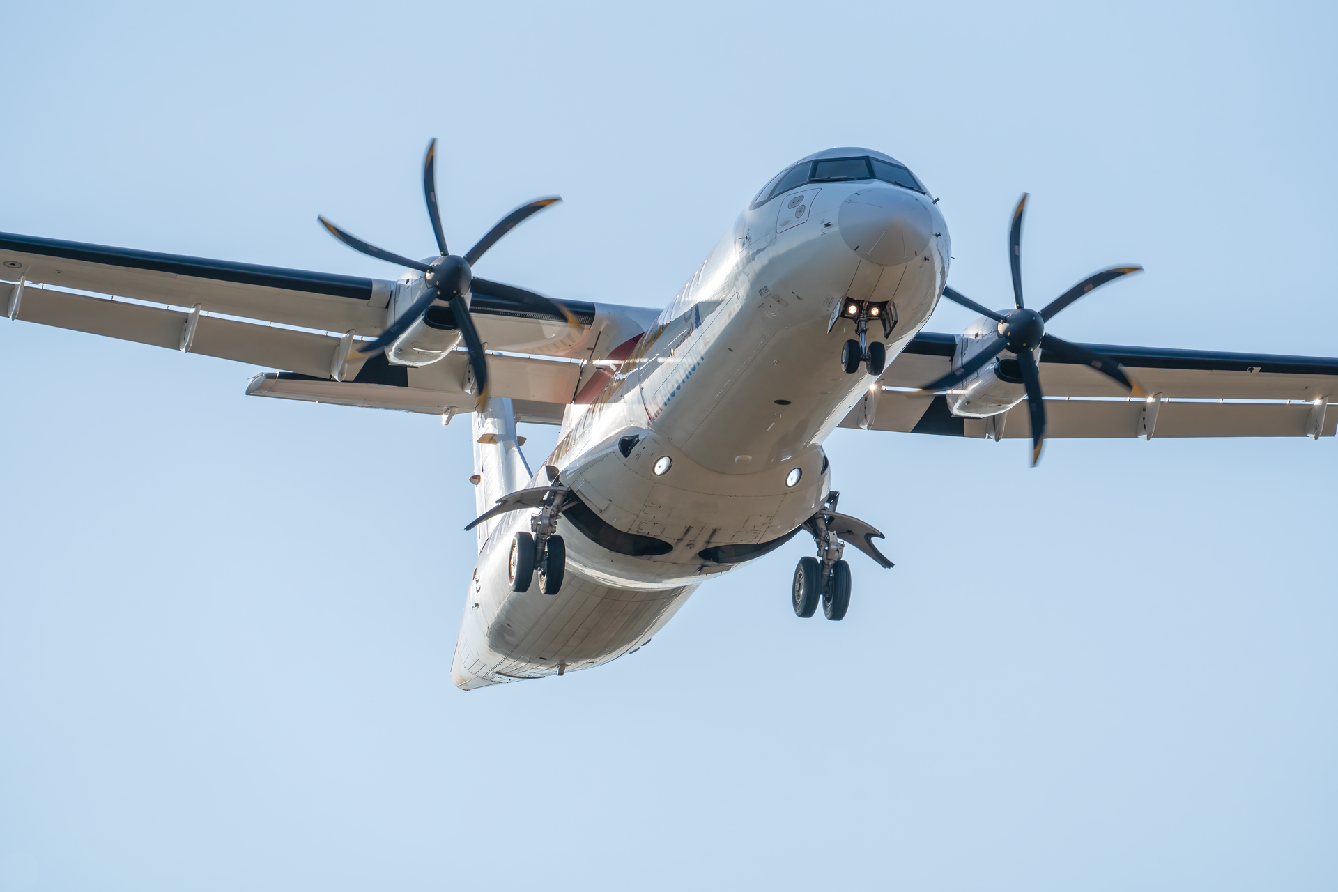 A close-up view of an ATR 72 aircraft approaching for landing under clear skies.