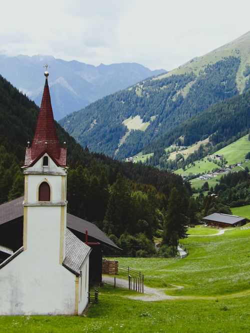 Free Charming rural church amidst lush mountains in Trentino-Alto Adige, Italy. Stock Photo