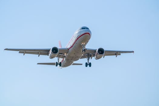 An Airbus A320 in flight descending over Manises, Valencia. Clear blue sky.