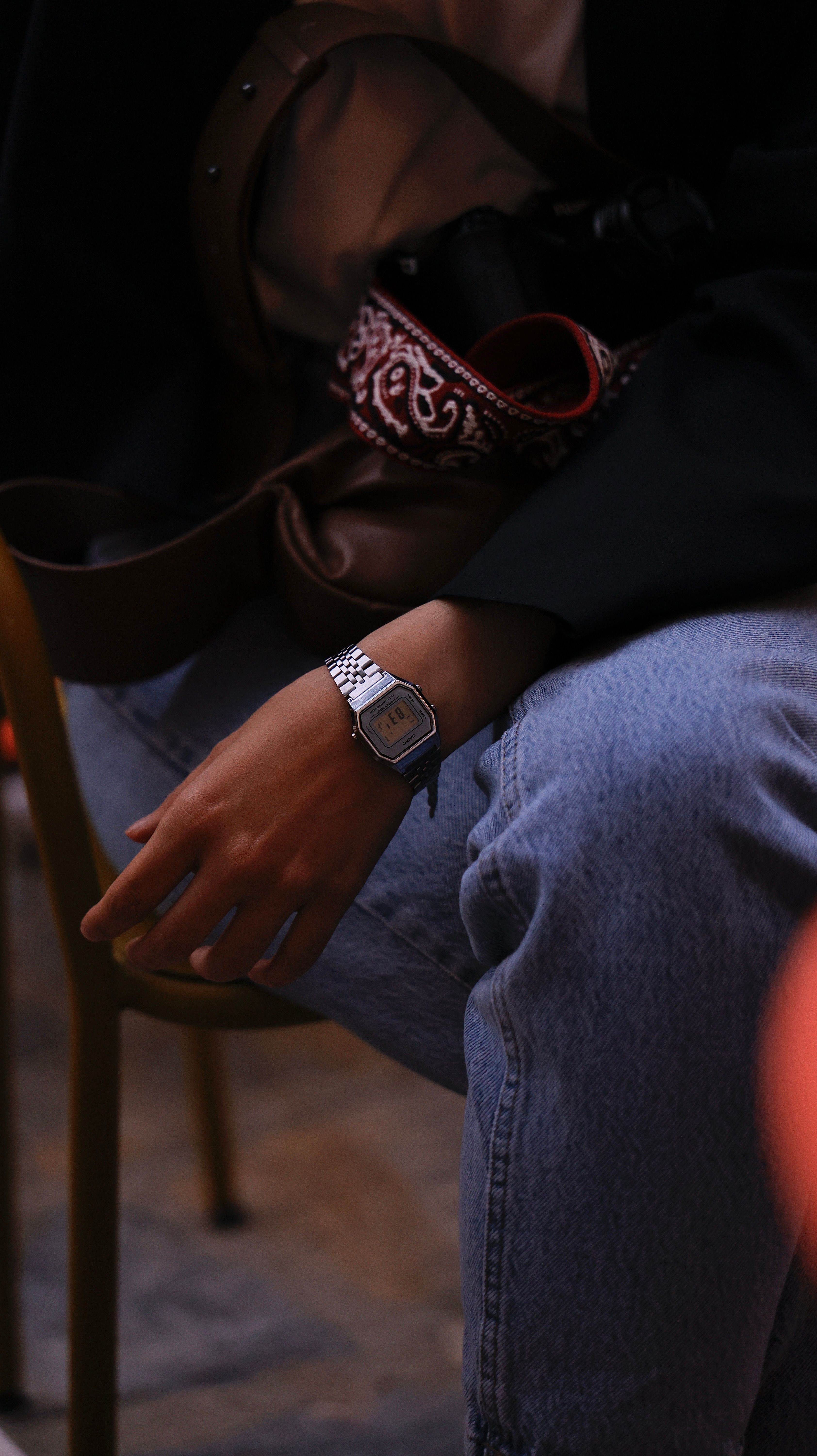 Close-up of a person in casual attire wearing a modern watch, sitting outdoors.