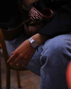 Close-up of a person in casual attire wearing a modern watch, sitting outdoors.