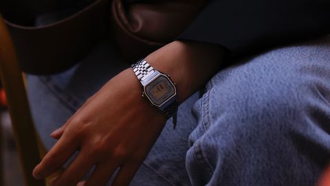 Close-up of a person in casual attire wearing a modern watch, sitting outdoors.