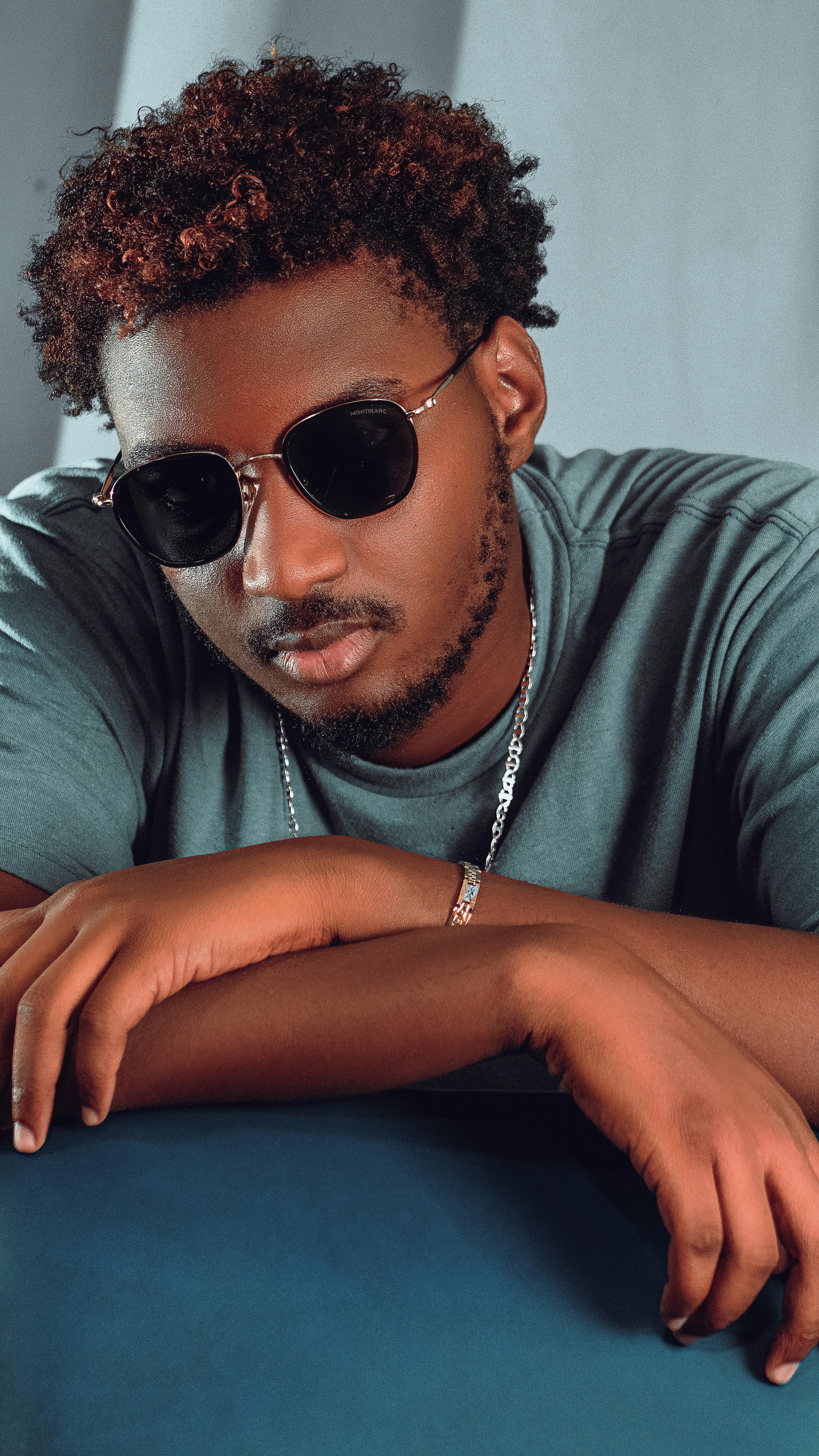 Stylish young man with sunglasses and jewelry embracing a modern streetwear look.
