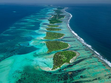 A breathtaking aerial shot of a Maldives atoll with vibrant blue waters and green islands.