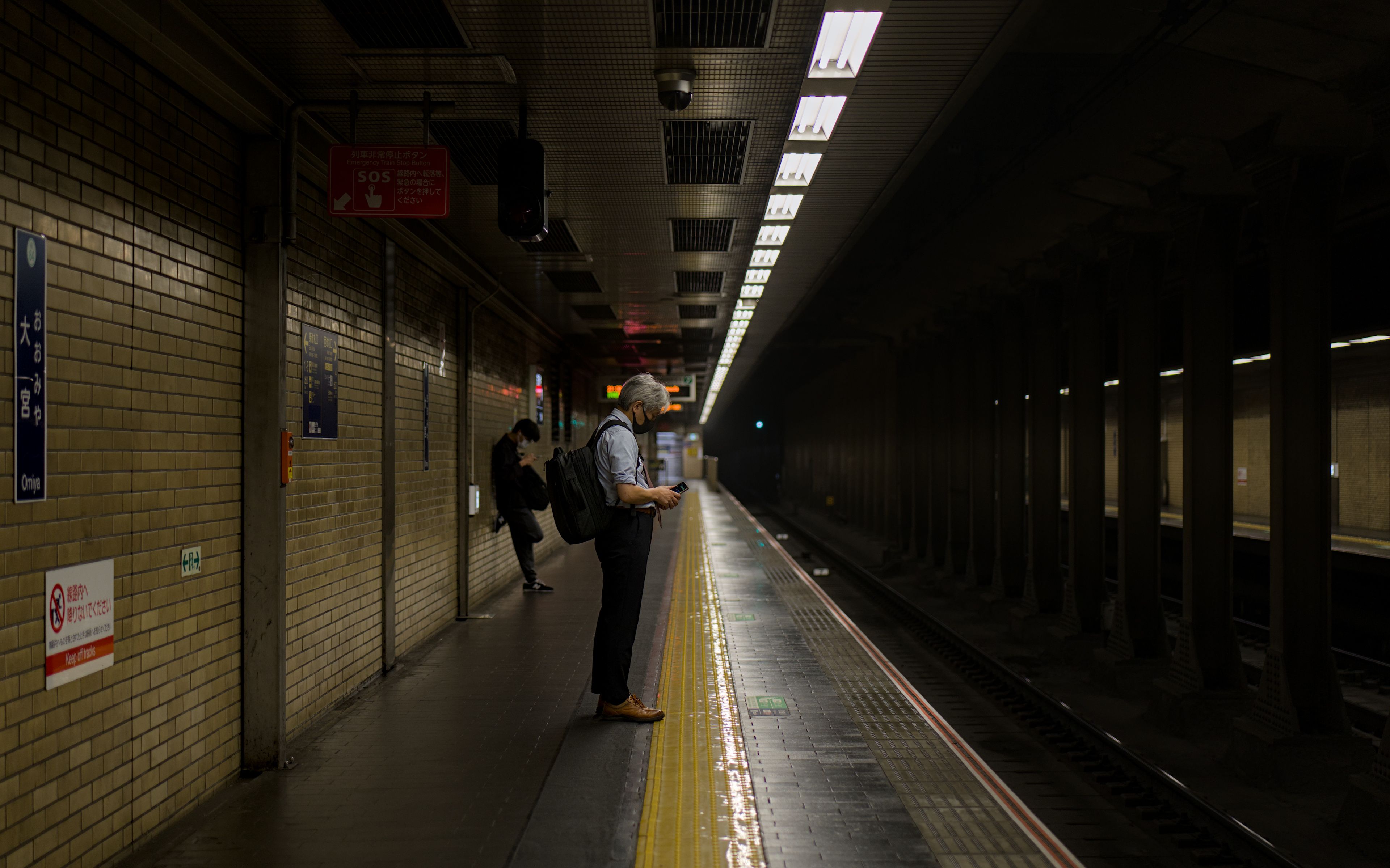 A man waits on a subway platform in Kyoto, Japan, during the night.