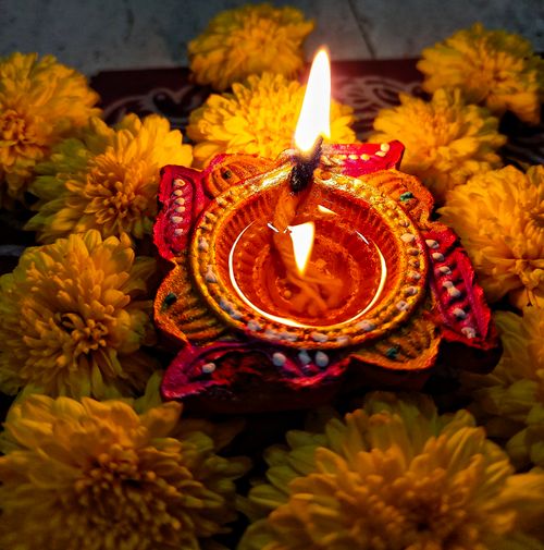 Free A beautifully crafted Diwali diya surrounded by vibrant yellow marigold flowers, symbolizing festival of lights. Stock Photo