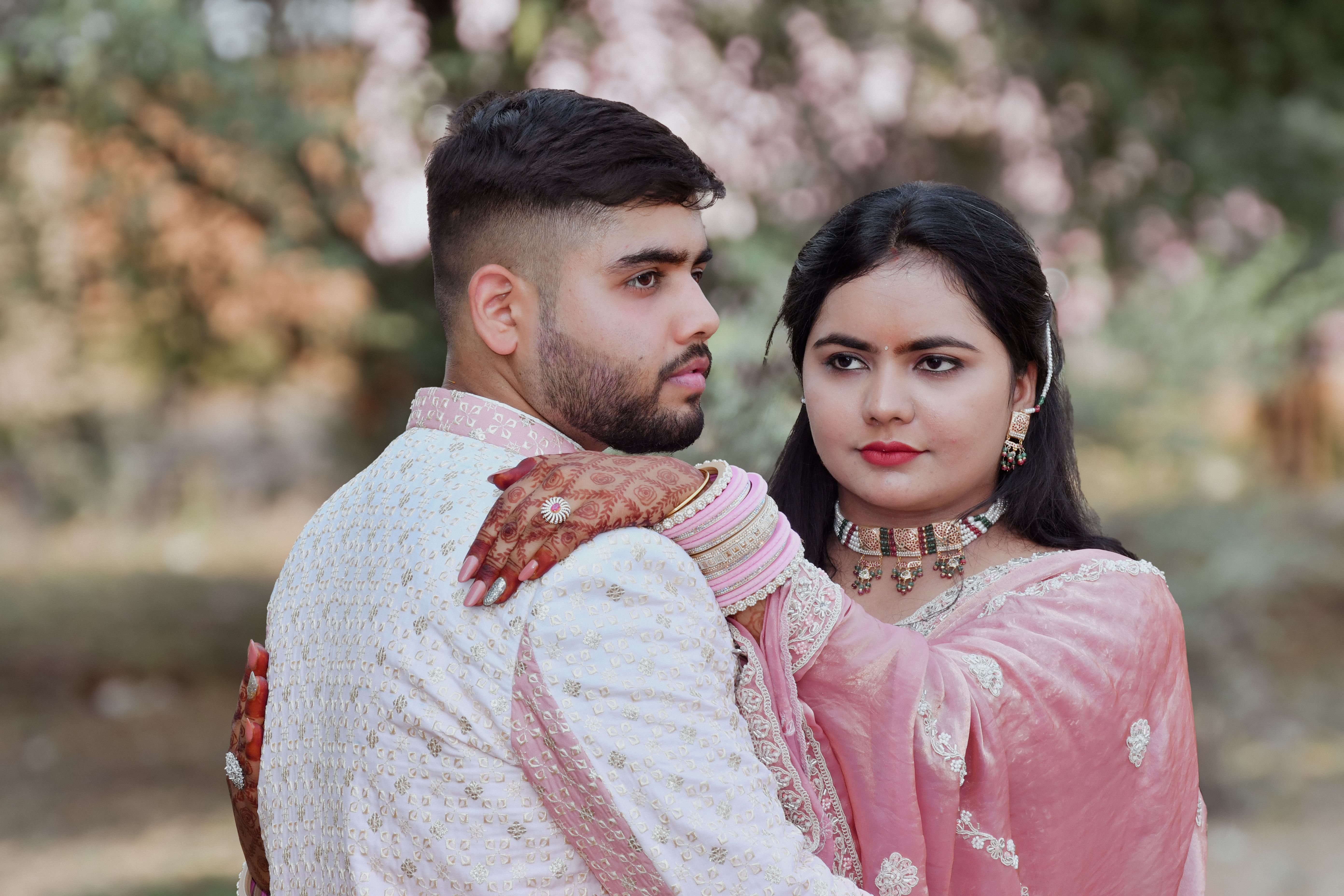 A couple in traditional attire embracing in a serene outdoor setting, exuding elegance and cultural richness.