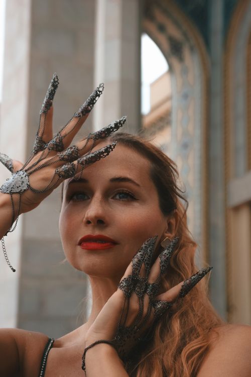 Free A woman with elaborate lacy hand accessories poses against an ornate architectural backdrop. Stock Photo