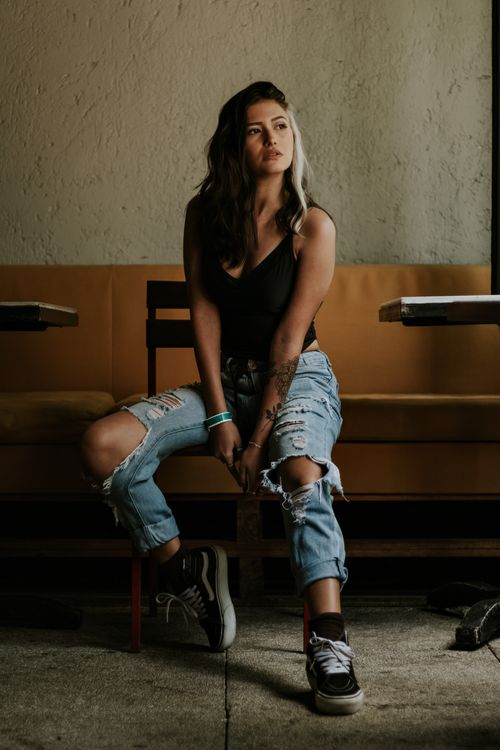 Free A fashionable woman posing indoors in ripped denim jeans, embodying modern style and allure. Stock Photo