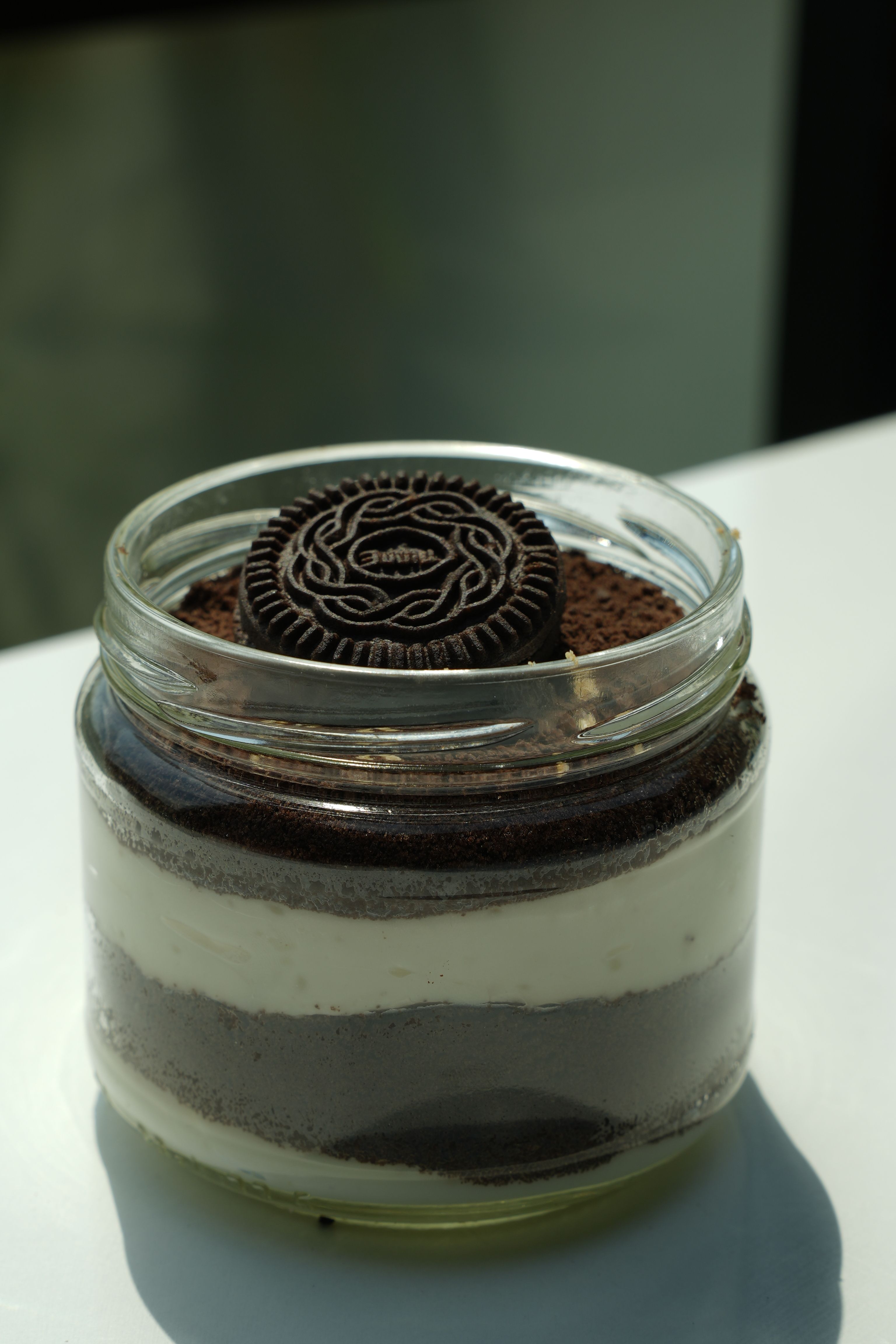 Oreo cookies fully dipped in glossy dark chocolate with delicate white chocolate drizzle, soft pink and cream backdrop, luxury bakery styling, hyperrealistic close-up