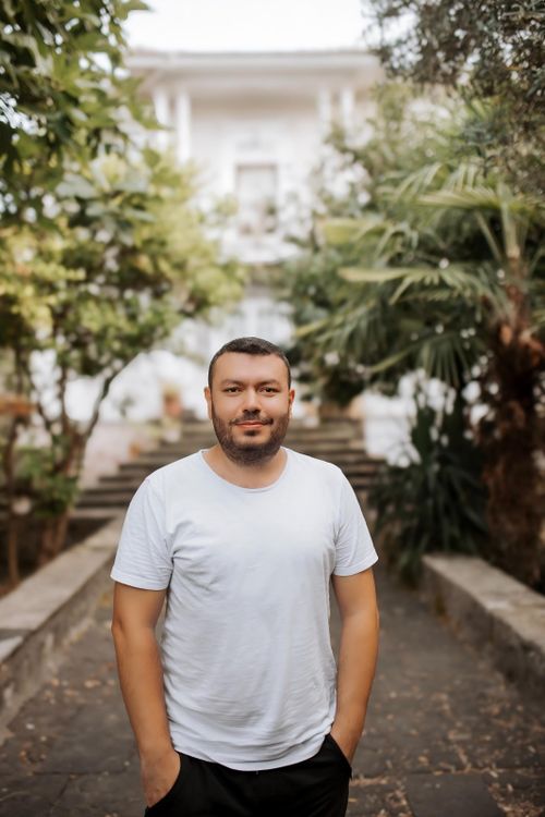 Free Adult man in white t-shirt standing outside in lush tropical garden. Stock Photo