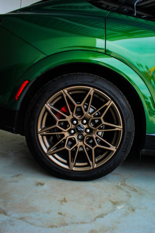 Free Close-up of a green car showcasing its bronze alloy wheel design and stylish curves. Stock Photo