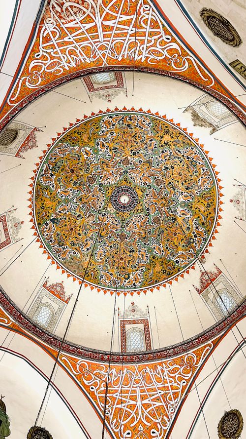 Free Beautifully decorated dome interior featuring Islamic calligraphy and vibrant patterns. Stock Photo