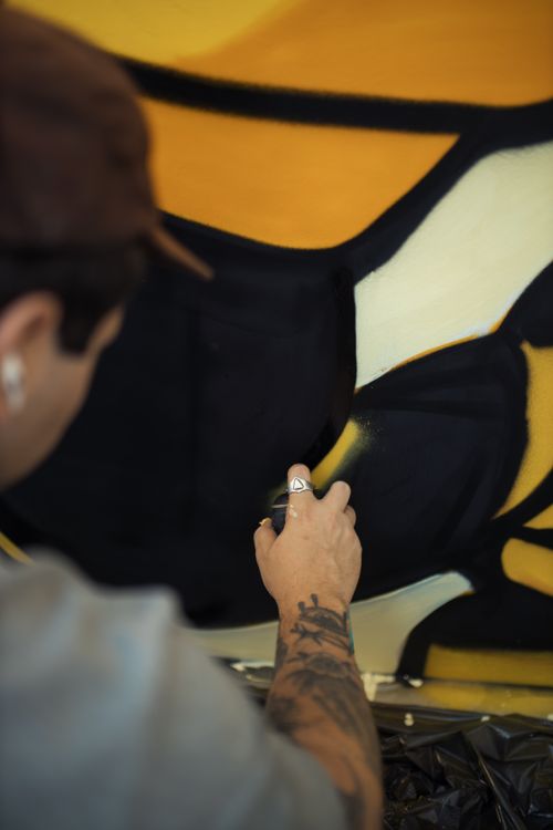Free A tattooed artist skillfully creating a vibrant mural with spray paint, showcasing artistic expression. Stock Photo