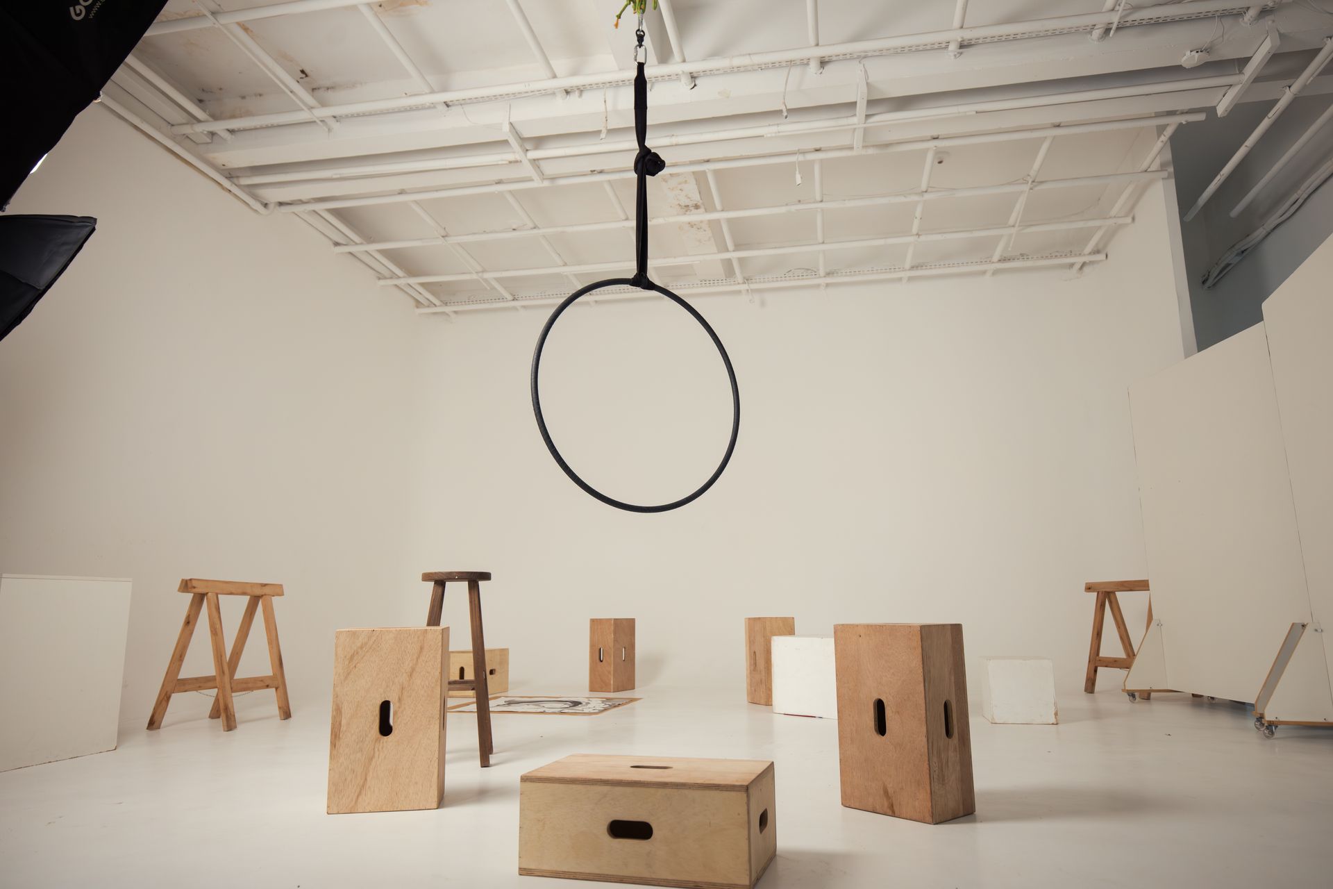 Spacious photography studio equipped with props and aerial hoop for artistic shoots.