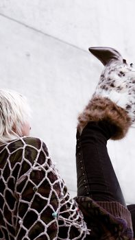Modern fashion portrait featuring fur boots and knitwear against a concrete backdrop, perfect for style inspiration.