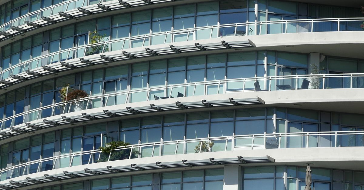 Close-up view of a modern apartment building with curved glass windows and balconies.