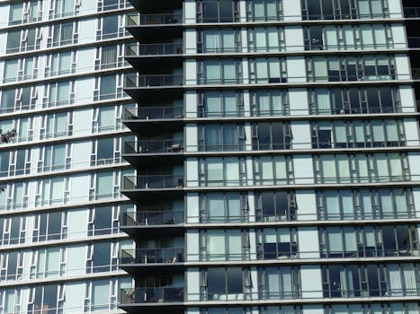 Close-up of a modern skyscraper facade showing glass windows and balconies on a sunny day.