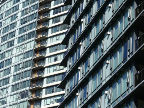 A contemporary pair of high-rise residential buildings with sleek glass facades reflecting urban architecture.