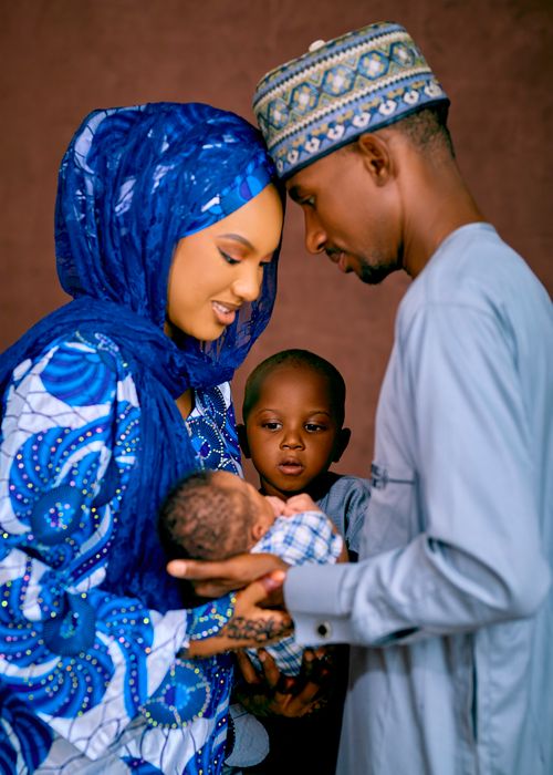 Free A beautiful Nigerian family warmly embracing their newborn baby in traditional attire. Stock Photo