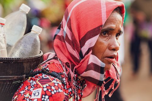 Free A Vietnamese woman in traditional attire carrying a basket of recycled bottles. Captured outdoors. Stock Photo